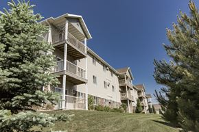 Bismarck apartment for rent - an apartment building with a lawn and trees in front of it. Bismarck, ND Sunset Ridge Apartments