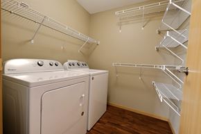 Fargo apartment for rent - a spacious laundry room with a washer and dryer and a closet with shelves. Fargo, ND Urban Plains Apartments