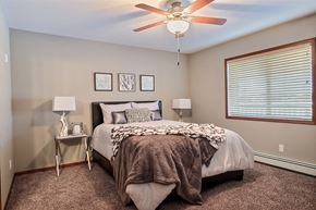 Fargo townhouse for rent - a bedroom with a large bed and a ceiling fan. Fargo, ND Urban Plains Apartments