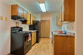 Fargo apartment for rent - a kitchen with black appliances and wooden cabinets. Fargo, ND Westcourt Apartments