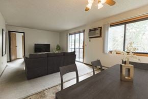 Bismarck apartment for rent - Bismarck, ND Eagle Sky I. A dining room with a black table with four chairs. The glass sliding door in the background brightens the room and living room behind the table with natural light.