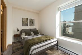 Bismarck apartment for rent - Bismarck, ND Norma Apartment serene bedroom featuring olive green bedding and a small window. The room exudes a tranquil ambiance