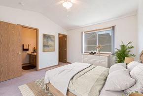 Bismarck apartment for rent - Bismarck Pebble Creek Apartments.  a bedroom with a large bed and a bathroom in the background. a large window fills the room with natural light