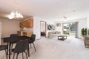 Bismarck apartment for rent - Sierra Ridge Apartments in Bismarck, ND | The space features an open floor plan with comfortable seating, a well-appointed dining table, and tasteful decor. The sliding glass door brightens the room w