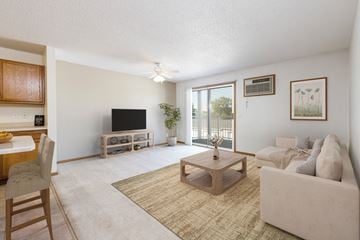 Bismarck apartment for rent - Bismarck, ND Sierra Ridge Apartments  a living room with white walls and a sliding glass door. Theres a white couch, coffee table, tv and bar stools at the counter in the dining area.