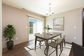 Bismarck townhouse for rent - Bismarck, ND Stonefield Townhomes. The space features a well-appointed dining table with 4 chairs, modern kitchen appliances, and tasteful decor. Bright natural light fills the room from the glass sliding door.