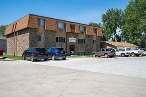 Bismarck apartment for rent - A parking lot in front of a building with cars parked. Bismarck, ND Arbor 406 Apartments