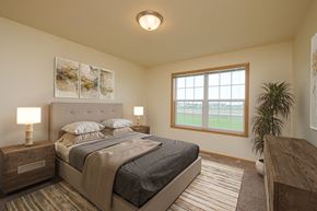 West Fargo townhouse for rent - A bedroom with a large bed and a window. West Fargo, ND Charleswood Townhomes.