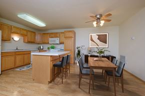 West Fargo townhouse for rent - A kitchen and dining room with a wooden table and chairs. West Fargo, ND Charleswood Townhomes.
