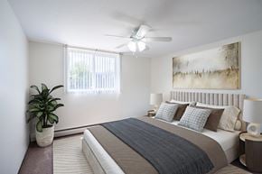Coon Rapids apartment for rent - a bedroom with a bed and a ceiling fan. Coon Rapids, MN Robinwood Apartments