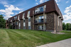 Bismarck apartment for rent - A brick apartment building with balconies and a green lawn in front. Bismarck, ND Belmont West Apartments