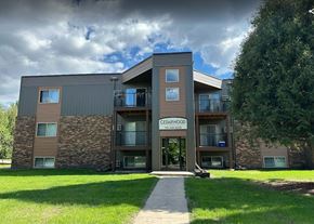 Grand Forks apartment for rent - a modern building named Cedarwood with a signboard and a walkway leading to the entrance. Grand Forks, ND Cedarwood Apartments
