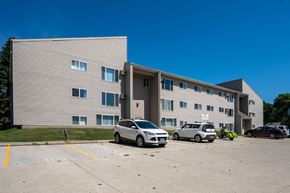 Bismarck apartment for rent - A grey building with a parking lot in front of it. Bismarck, ND Bradbury Apartments