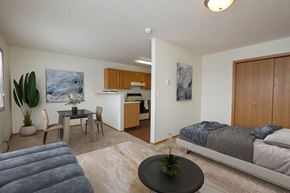 Fargo apartment for rent - Fargo, ND Ashbury Apartments. a bedroom with a bed a table and a chair and a kitchen in the background