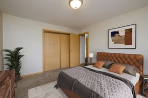 Fargo apartment for rent - a bedroom with a large bed and a potted plant. Fargo, ND Birchwood 2 Apartments