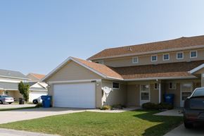 Fargo townhouse for rent - a tan house with a white garage door and a lawn. Fargo, ND Bluestem Townhome