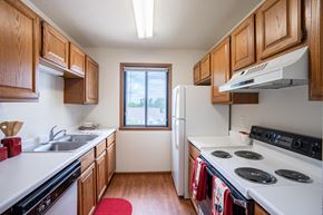 Fargo apartment for rent - a kitchen with white appliances and wooden cabinets and a window. Fargo, ND Briar Pointe Apartments