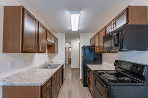 Fargo apartment for rent - Fargo, ND Cambridge Apartments. A kitchen with wood cabinets and a black stove top oven