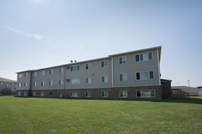 Fargo apartment for rent - Fargo, ND Cambridge Apartments. A large apartment building with a green lawn in front of it