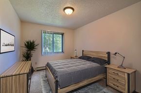 Fargo apartment for rent - a bedroom with a bed and a dresser and a window. Fargo, ND Chestnut Ridge Apartments