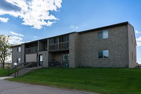 West Fargo townhouse for rent - an exterior view of a brick apartment building with green grass