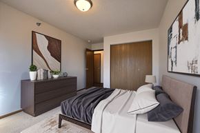 West Fargo apartment for rent - a bedroom with a bed and a dresser and a door to a bathroom. Fargo, ND Eagle Run Apartments