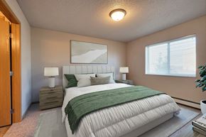 Fargo apartment for rent - a bedroom with a white bed and a green blanket. Fargo, ND East Bridge Apartments