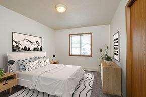 Fargo apartment for rent - Fargo, ND Flickertail Apartments. a bedroom with a white bed and a wooden dresser with a plant on it