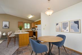 Fargo apartment for rent - Fargo, ND Flickertail Apartments a dining area with a small table and chairs and a kitchen in the background