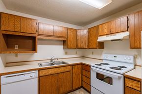 Fargo apartment for rent - an empty kitchen with white appliances and wooden cabinets. Fargo, ND Galleria 3 Apartments