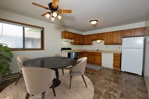 Fargo apartment for rent - Fargo, ND Gemstone Apartments. a dining area with a table and chairs and a kitchen with a refrigerator and dishwasher. A window fills the room with bright natural light