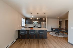 Fargo apartment for rent - a kitchen with an island with four chairs and a dining room with a table. Fargo, ND Granger Court Apartments