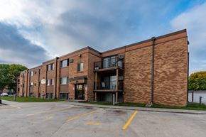 Fargo apartment for rent - a brick apartment building with a parking lot and a cloudy sky. Fargo, ND Hartford Apartments