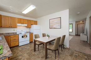 Fargo townhouse for rent - a kitchen with white appliances and a dining table with chairs. Fargo, ND Hazelwood Townhomes