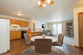 Fargo apartment for rent - Fargo, ND Hunters Run Apartments. A dining area with a table and four chairs and a kitchen in the background.