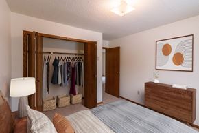Fargo apartment for rent - a bedroom with a closet and a bed and a dresser. Fargo, ND Huntington Apartments