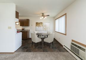 Fargo apartment for rent - Fargo, ND Islander Apartments. A dining area with a four chair table that has a cailing fan with a light above it. A window brightens the room with natural light. Theres also a kitchen in the background
