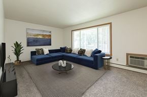 Fargo apartment for rent - Fargo, ND Islander Apartments. A living room with a large blue couch and a coffee table.  A large window brightens the room with natural light