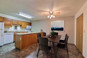 Fargo apartment for rent - a dining area with a table and chairs and a kitchen in the background. Fargo, ND Kennedy Apartments