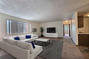 Fargo apartment for rent - Fargo, ND Kingswood Apartments. A living room with a large white couch and a coffee table. A long window brightens the room with natural light
