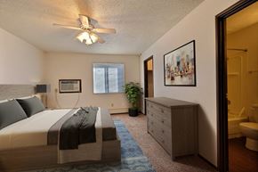 Fargo apartment for rent - Fargo, ND Kingswood Apartments.  A bedroom with a bed and a dresser a large walk in closet is in the back corner of the room along with a window to brighten the room with natural light