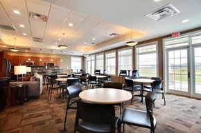 West Fargo apartment for rent - Fargo, ND Lake Crest Apartments. A large room with tables and chairs and a kitchen in the background