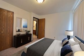 Fargo apartment for rent - a bedroom with a bed and a dresser and a mirror. Fargo, ND Pacific South Apartments