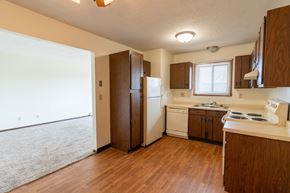 West Fargo apartment for rent - Kitchen with white appliances and brown cabinets a small window above the sink brightens the room with natural light at Parkwest Gardens West Fargo, ND