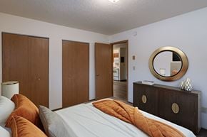 Fargo apartment for rent - a bedroom with a bed and a dresser and a mirror. Fargo, ND Parkwood East and West Apartments