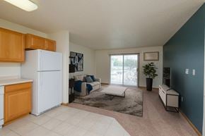 Fargo apartment for rent - A kitchen and living room with a refrigerator and a sliding glass door. Fargo, ND Pinehurst Apartments.