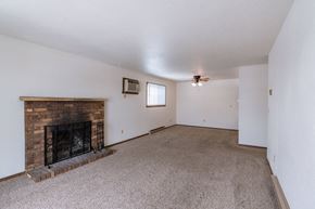 Fargo apartment for rent - a living room with a brick fireplace and a carpeted floor. Fargo, ND Plumtree Apartments