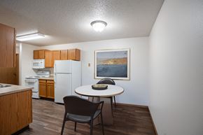 West Fargo apartment for rent - a kitchen and dining area with a table and chairs and a refrigerator. Fargo, ND Prairie Park Apartments