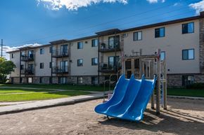 West Fargo apartment for rent - Fargo, ND Prairie Park Apartments. A playground with two blue slides in front of an apartment building
