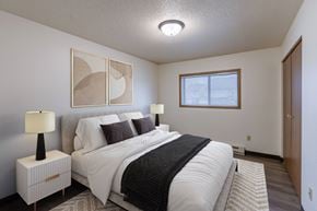 Fargo apartment for rent - a bedroom with a large bed and a window. Fargo, ND Prairiewood Courts Apartments